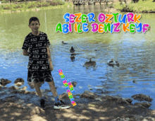 a boy standing next to a body of water with the words sezer ozturk abile deniz keyf written above him