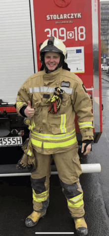 a fireman giving a thumbs up in front of a fire truck