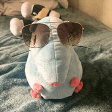 a stuffed animal wearing sunglasses is laying on a bed