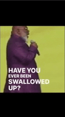 a man in a purple suit is holding a microphone and says " have you ever been swallowed up ? "