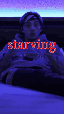 a man in a hoodie with the word starving in red letters