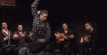 a woman in a polka dot dress is dancing in front of a sign that says ' flamenco en vivo '