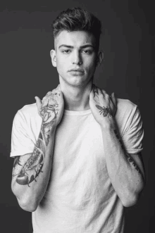 a black and white photo of a young man with tattoos on his arms and neck