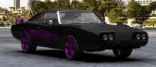 a black dodge charger with purple wheels and a purple wing