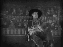 a man in a cowboy hat is standing in front of a crowd in a black and white photo .