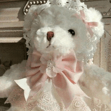 a white teddy bear wearing a pink bow and a lace hat .