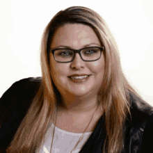 a woman wearing glasses and a black jacket smiles