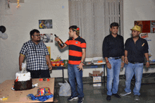 a group of men are standing around a table with a cake and a sign that says pirate party