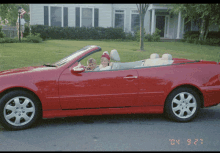 a red convertible is parked in front of a house with the date 04 3:27