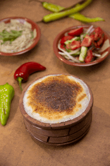 a bowl of food sits on a table next to vegetables