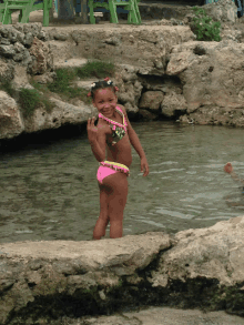 a young girl in a pink bikini stands in the water