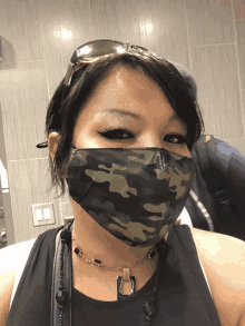 a woman wearing a camouflage face mask with sunglasses on her head