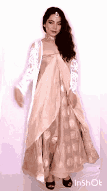 a woman wearing a long dress and a white jacket