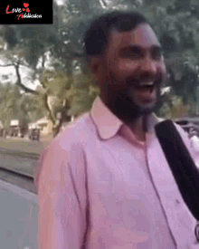 a man in a pink shirt is talking into a microphone in front of a sign that says love production