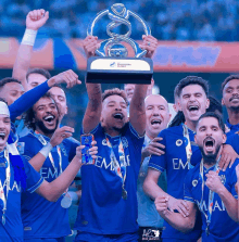 a group of soccer players holding up a trophy with em on their jerseys