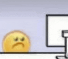 a yellow smiley face is sitting on a desk next to a computer .