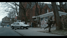 a ford car is parked on the side of the road in front of a building with graffiti on it