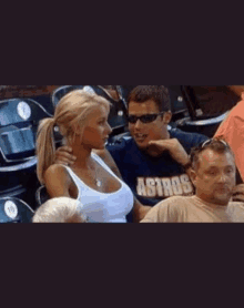 a man wearing an astros shirt sits next to a woman in a white tank top