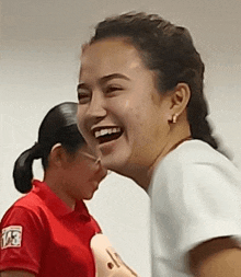 a woman is laughing while holding a mannequin and another woman is laughing behind her .