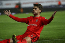 a soccer player wearing a vodafone jersey is laying on the field .