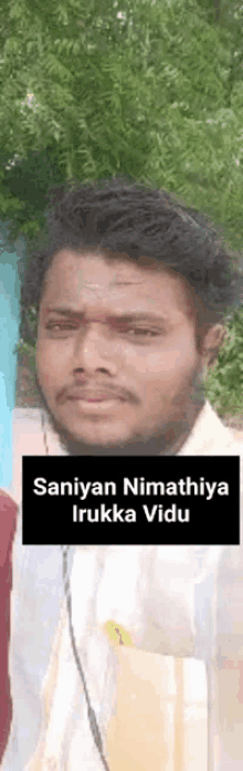 a man with a beard is standing in front of a tree and a sign that says saniya nimathiya irukka vidu