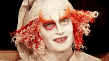 a close up of a person 's face with red hair and white face paint