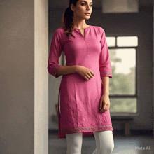 a woman in a pink dress and white pants is standing in a room