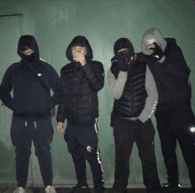 a group of young men wearing hoodies and masks standing next to each other with one wearing a nike hoodie