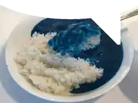 a bowl of rice and blue sauce with a spoon