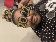 a woman wearing a mickey mouse shirt and a headband that says happy new year 2022