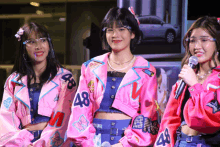 three girls wearing pink jackets with 48 on them