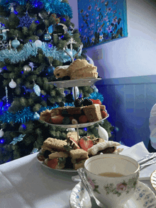 a christmas tree is in the background behind a table with a cup of tea