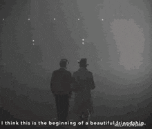 two men are standing next to each other in a dark room looking at the stars in the sky .