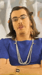 a man wearing glasses and a pearl necklace has a watch on his wrist