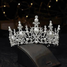 a tiara with pearls and rhinestones sits on a jewelry display