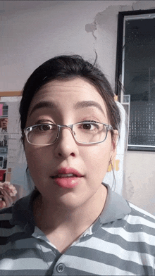 a woman wearing glasses and a striped shirt making a funny face