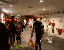 a group of soccer players are walking down a hallway with a sign that says " the walk of champions "