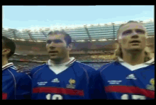 a group of soccer players are standing in front of a stadium wearing blue jerseys with the number 10 on them