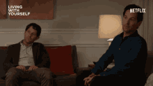 two men are sitting on a couch with a netflix logo in the background