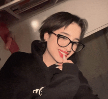 a girl wearing glasses and a black hoodie with the letter t on it