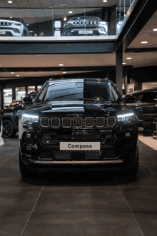 a black jeep compass is parked in a car dealership