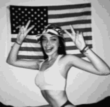 a black and white photo of a woman wearing a hat standing in front of an american flag