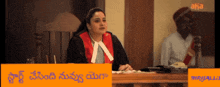 a woman in a judge 's robe sits at a desk in front of a sign that says ' a '