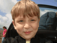 a young boy is smiling while sitting in the back of a car