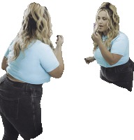 a woman in a blue shirt is looking at herself in the mirror