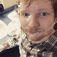 a man with shaving cream on his face is taking a selfie in a bathroom .