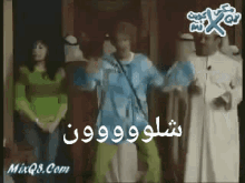 a group of people are standing next to each other in a room with arabic writing on the screen .