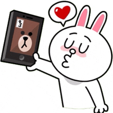 a cartoon rabbit is holding a cell phone with a bear on the screen .