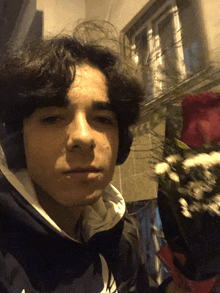 a young man wearing headphones holds a bouquet of flowers in front of his face