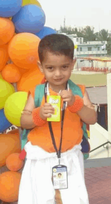 a young boy is holding a box of juice in front of a bunch of balloons